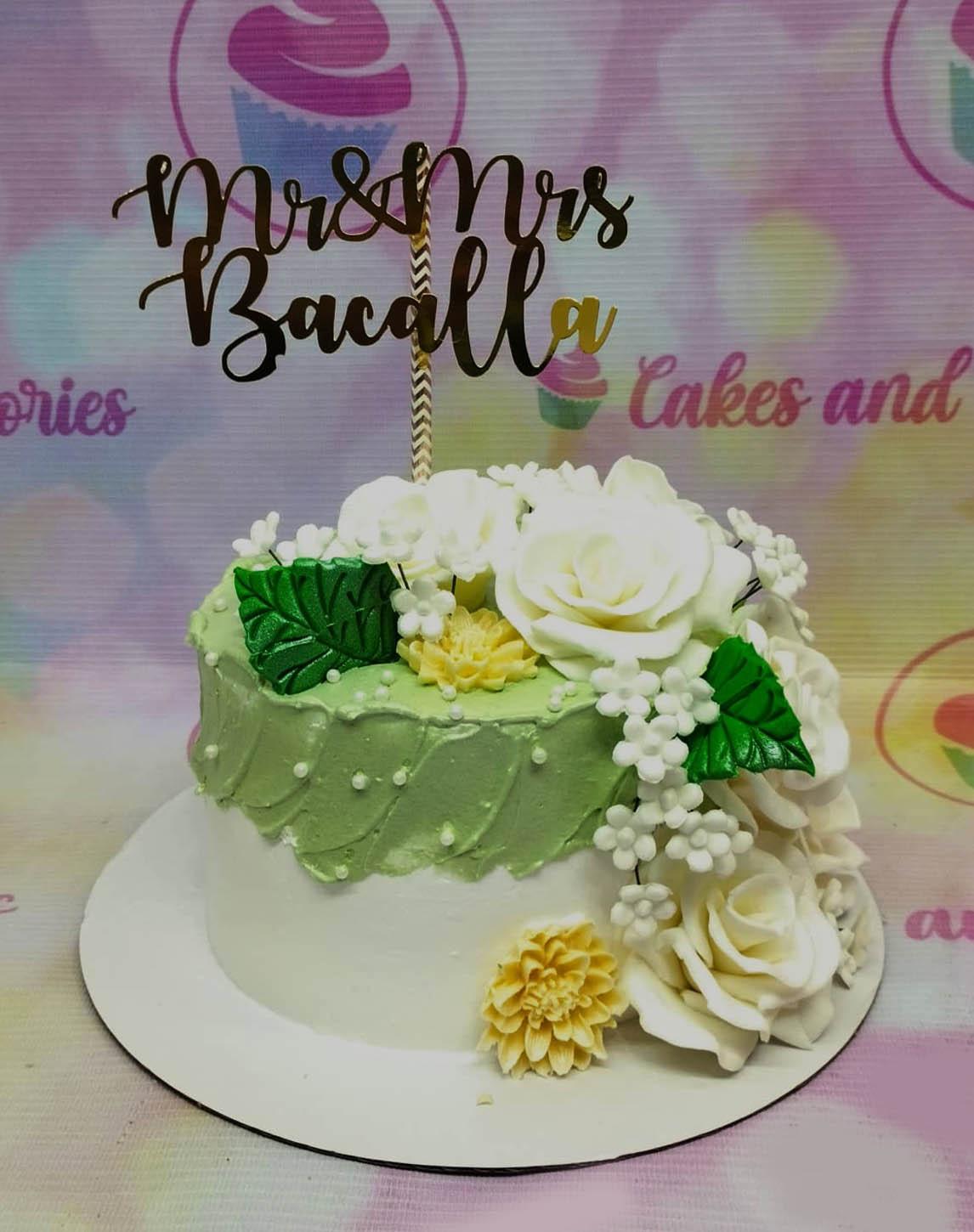 White and green floral wedding cake with a gold Mr and Mrs Bacalla topper and gumpaste roses.