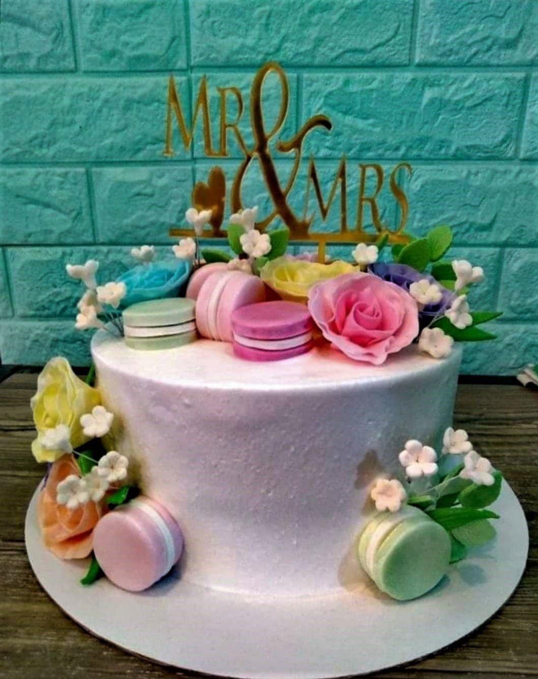 White 1-tier wedding cake with colorful edible roses, macarons, and a gold Mr & Mrs topper.