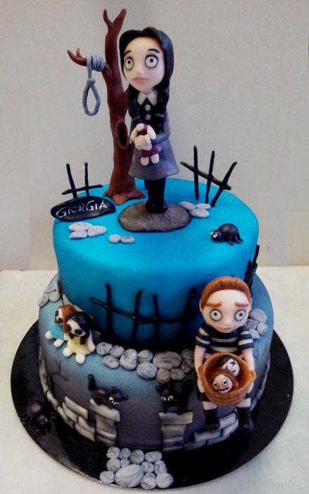 Two-tier Wednesday Addams themed fondant cake in blue and gray with 3D fondant characters, a spooky tree, and stone accents.