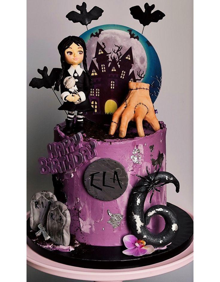 Purple Wednesday Addams themed birthday cake with a fondant Wednesday figure, Thing hand, and spooky haunted house backdrop.