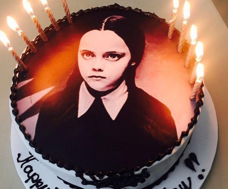 Wednesday Addams themed birthday cake with a large character printout, black icing borders, and lit candles.