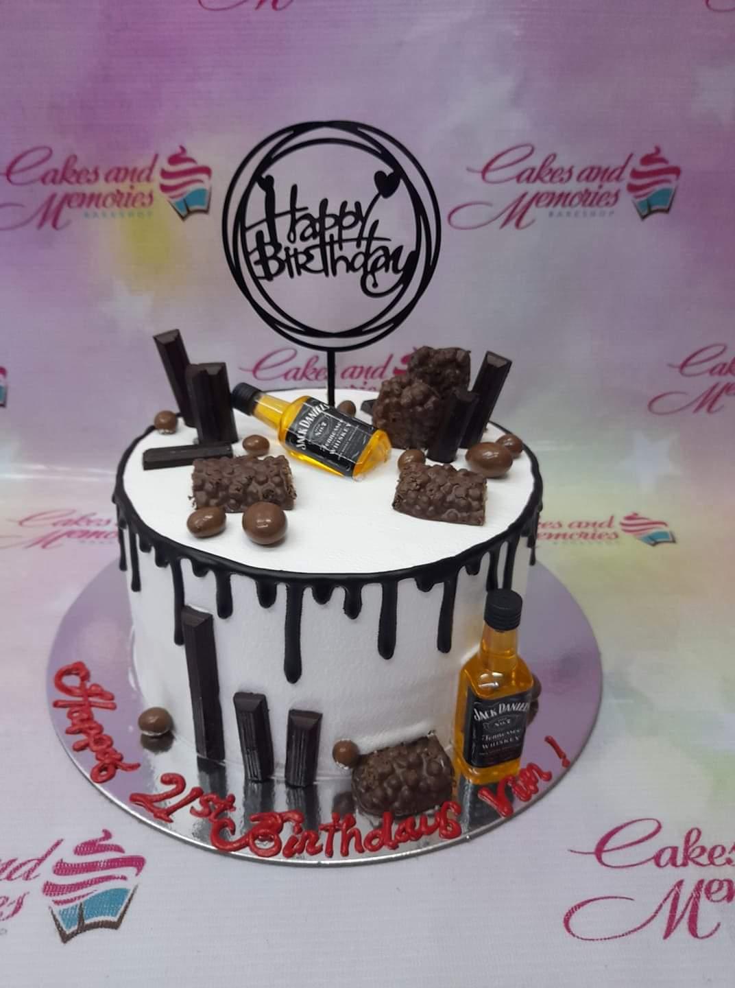White 1-tier whiskey themed birthday cake with chocolate drip, Jack Daniel's mini bottles, and assorted chocolate bars.