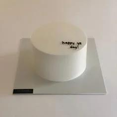 Minimalist white bento cake with black piped icing text reading happy yz day on a silver square board.
