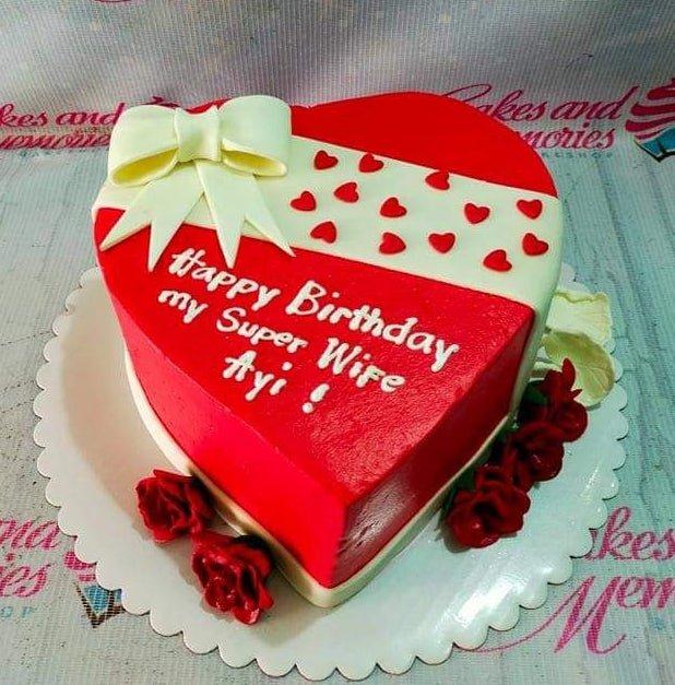 Heart-shaped red and white birthday cake for a wife with a large white fondant bow and red heart accents.