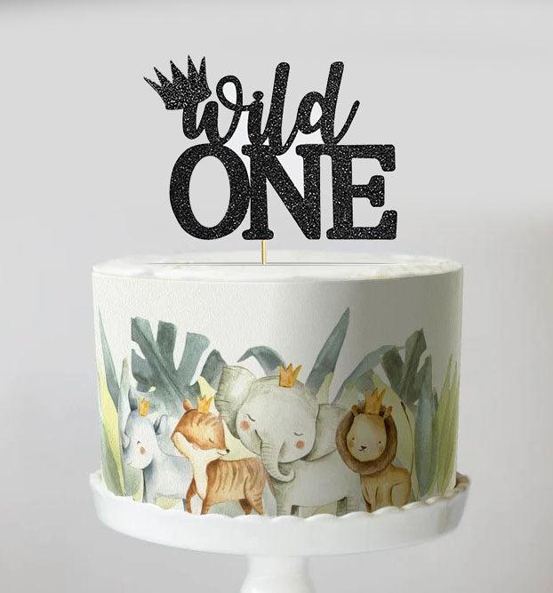 White 1-tier safari animal birthday cake with a black glitter Wild One topper and watercolor jungle animal side wrap.