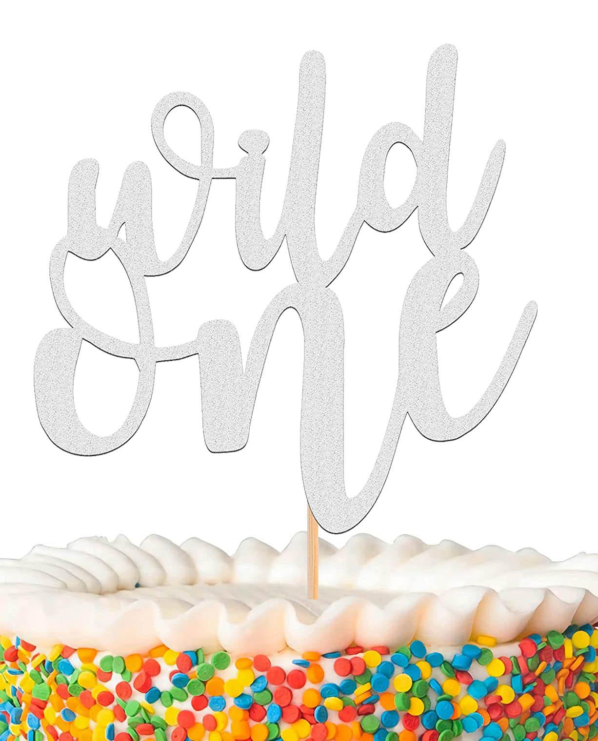 White 1-tier birthday cake with colorful confetti sprinkles and a silver glitter Wild One topper.