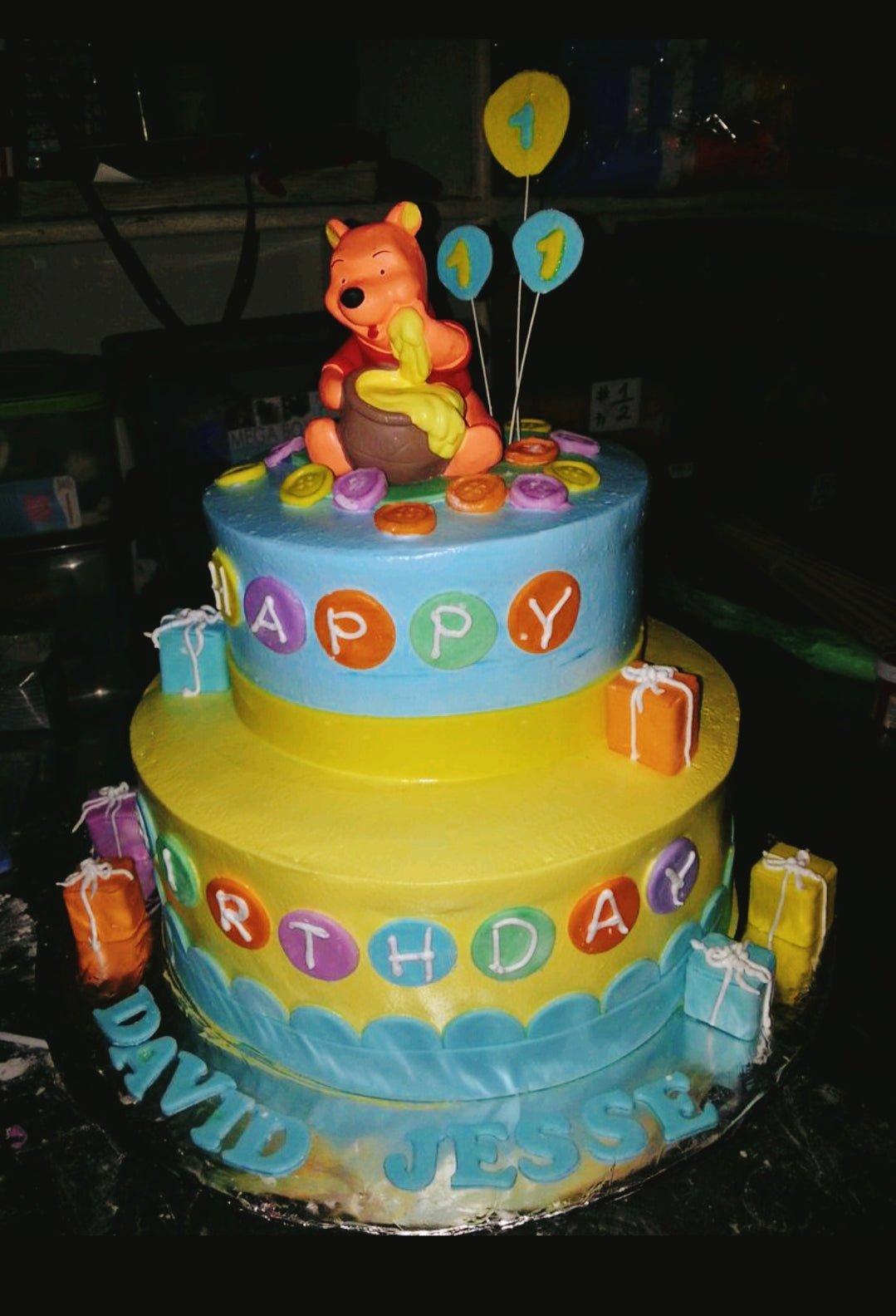 Winnie the Pooh themed 2-tier birthday cake in blue and yellow with fondant gift boxes and character topper.