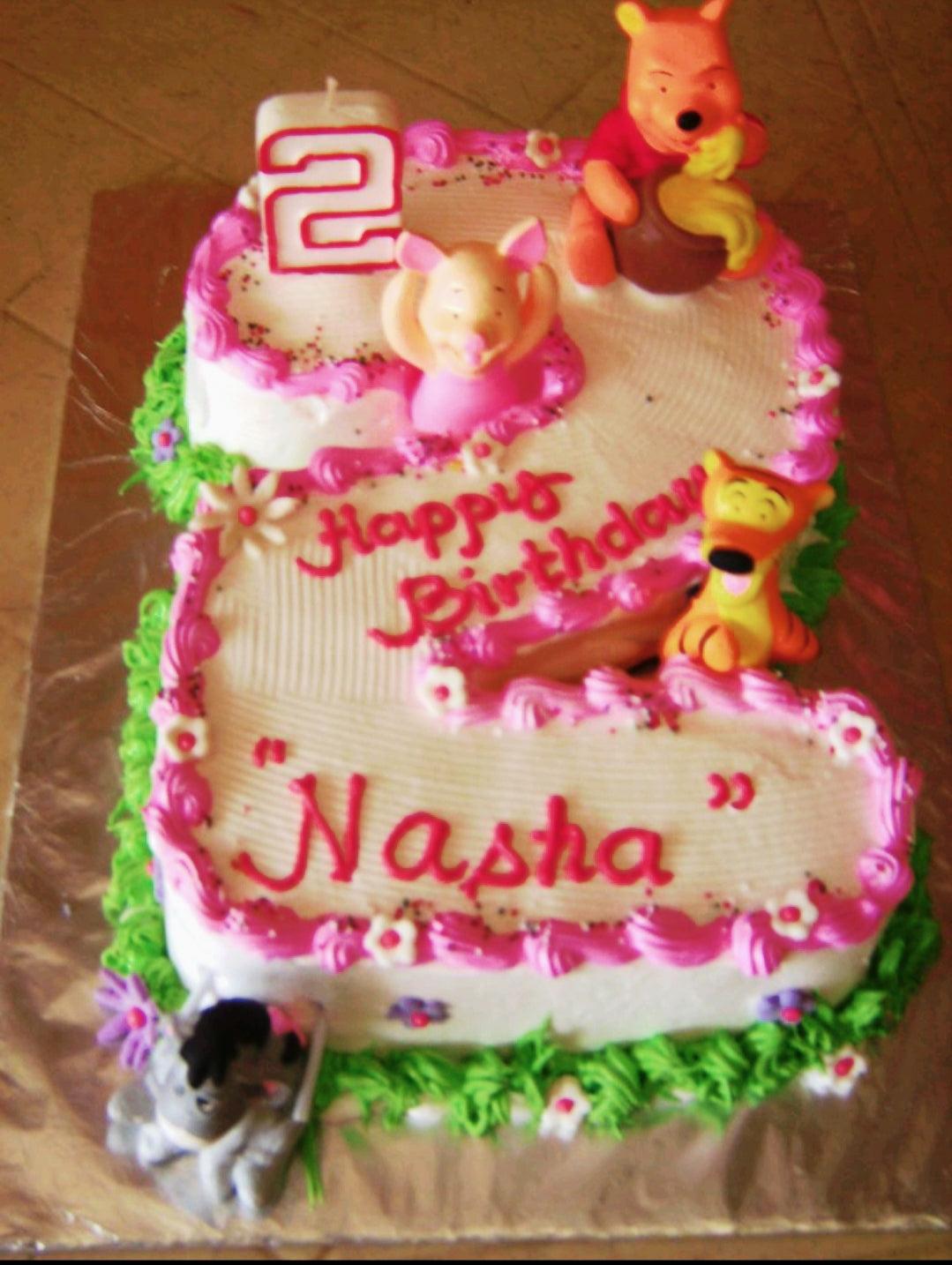 Winnie the Pooh themed number 2 shaped cake with pink icing borders and fondant character figures of Pooh, Piglet, Tigger, and Eeyore.