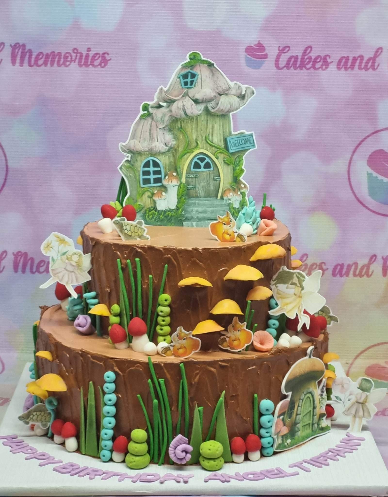 Two-tier brown woodland fairy cake with mushroom house topper, fairies, squirrels, and green fondant grass accents.