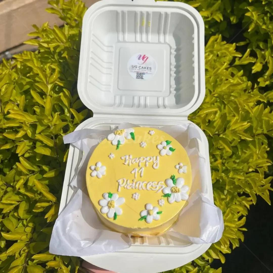Yellow bento cake with white piped icing daisies and a Happy 11 Princess message in white icing.