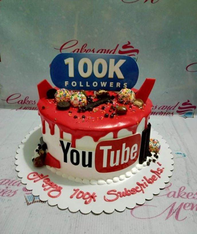 YouTube themed cake with red drip icing, 100K followers topper, and chocolate decorations on a white base.