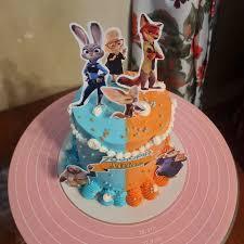 Zootopia themed birthday cake with blue and orange icing, featuring Judy Hopps and Nick Wilde printout toppers.