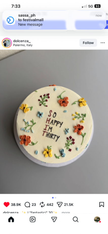 White minimalist birthday cake with colorful piped icing flowers and a humorous 'So Happy I'm Thirty' message.