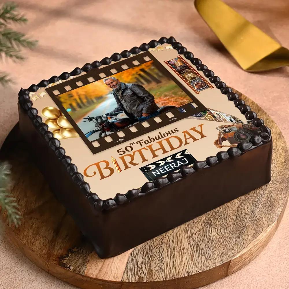 Square chocolate birthday cake with a film strip photo printout and black icing rosettes for a 50th birthday celebration.
