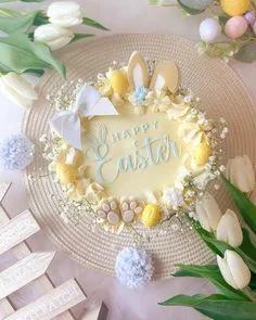 Light yellow Easter cake with bunny ears, paws, and yellow eggs, decorated with white baby's breath and a large white bow.