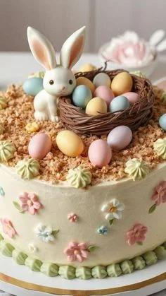 Easter themed cake with a white fondant bunny, a chocolate nest with pastel eggs, and piped icing flowers on a cream base.