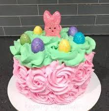 Pink rosette cake with green icing top, featuring a pink bunny peep and colorful glittery Easter egg toppers.