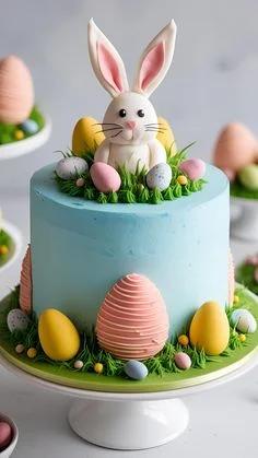 Light blue Easter bunny cake with a 3D fondant rabbit topper, pink and yellow eggs, and green icing grass.
