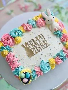 Rectangular white cake with colorful pastel icing rosettes and a gold Happy Easter bunny topper with a 3D bunny figurine.
