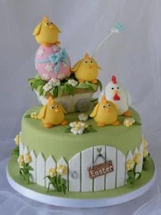 Green fondant Easter cake featuring a white picket fence, yellow chicks, a mother hen, and a decorated pink Easter egg topper.