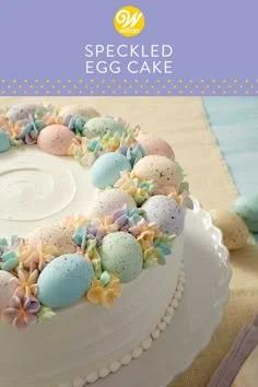 White round cake with a wreath of pastel speckled Easter eggs and colorful icing flowers.