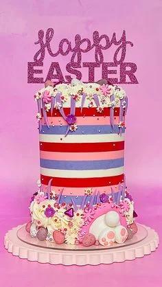 Tall striped Easter cake with pink, red, and purple bands, white icing dollops, and a fondant bunny butt topper.