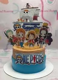 One Piece themed birthday cake with blue and tan icing featuring Luffy and the Straw Hat crew printouts and a pirate ship topper.