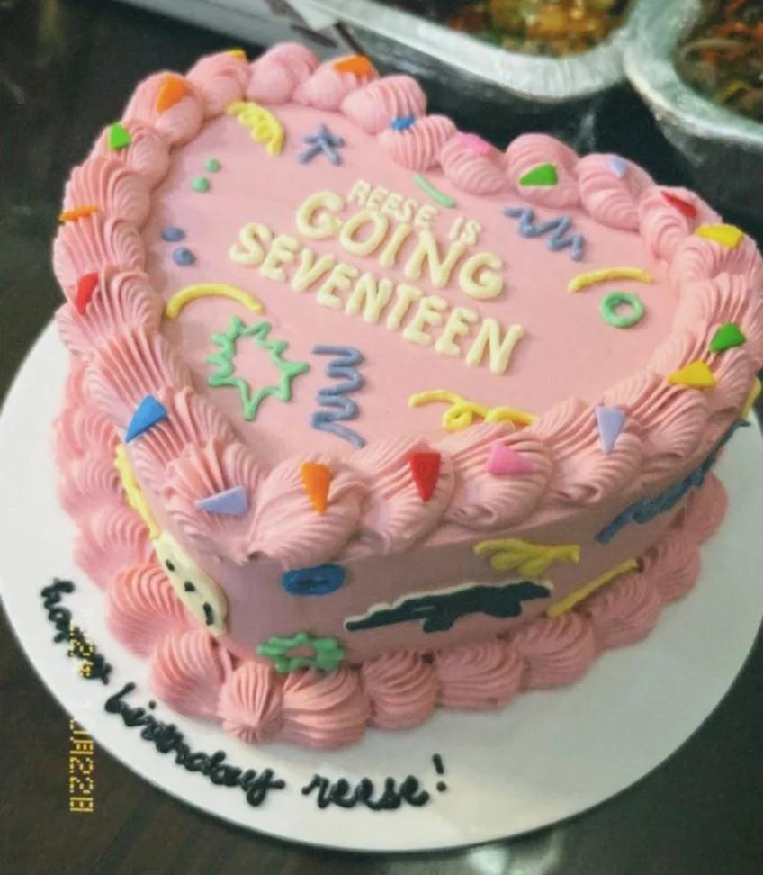 Heart-shaped pink minimalist cake with colorful icing doodles and a birthday message for Reese.