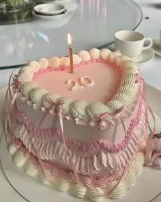 Heart-shaped pink vintage lambeth cake with intricate ruffles, pink satin ribbons, and a gold number 20 candle.