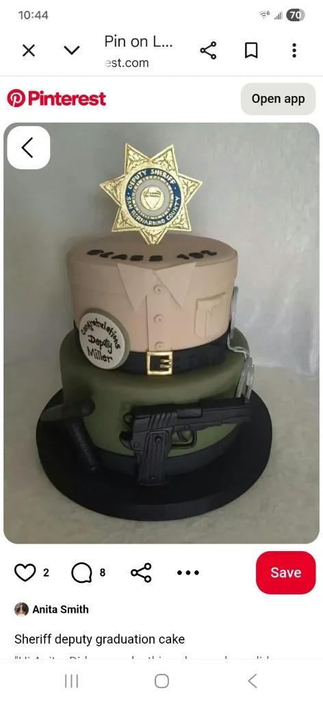 Two-tier police graduation cake with tan and olive green fondant, featuring a sheriff badge, handcuffs, a pistol, and a baton.