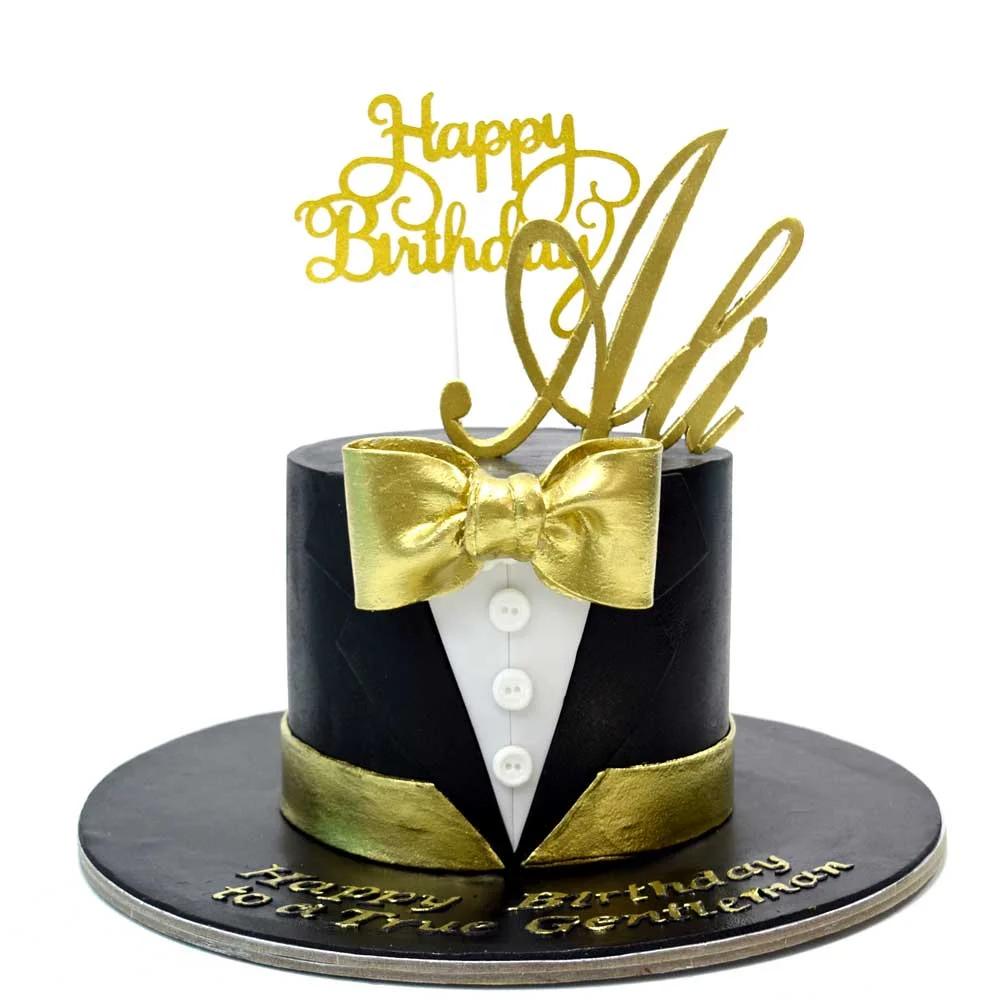 Black tuxedo-style birthday cake with a gold bow tie, white shirt buttons, and a gold Happy Birthday Ali topper.